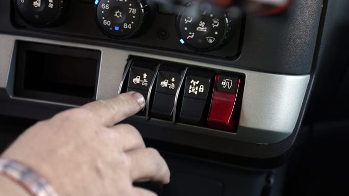 Photo showing a finger pushing a switch on a truck dashboard to control the SmartValve system